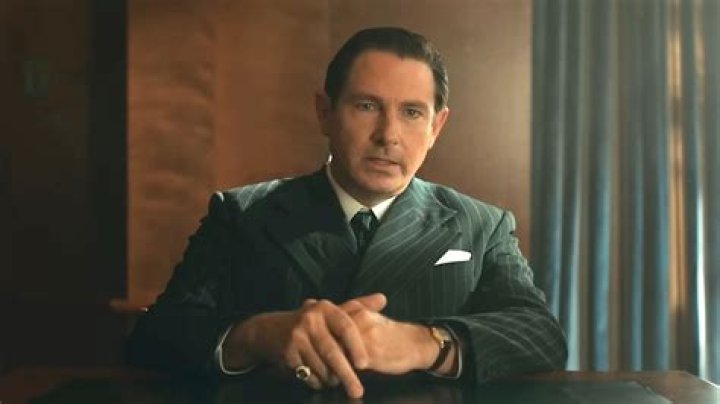 Derek Cecil as Dr. Robert Donatti in Apple TV Plus Lessons in Chemistry is sitting at a desk.
