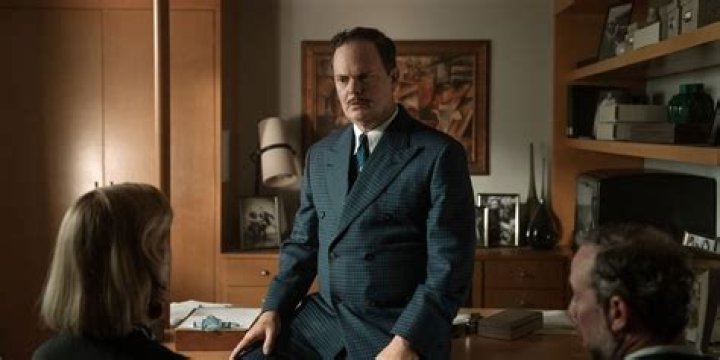 Rainn Wilson as Phil Lebensmal in Apple TV Lessons in Chemistry is talking to someone off camera.