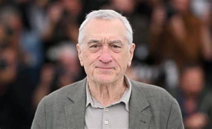 Robert De Niro is standing on the red carpet. 